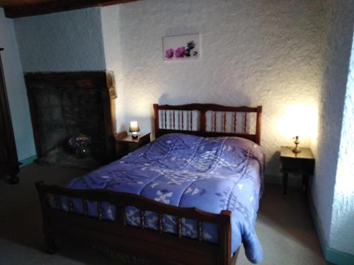 a bedroom with a bed with a blue comforter at gite chez Régine in Marcenat