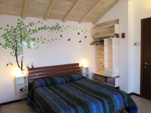 1 dormitorio con 1 cama y un árbol en la pared en B&B La casa dei frutti di bosco, en Garlasco
