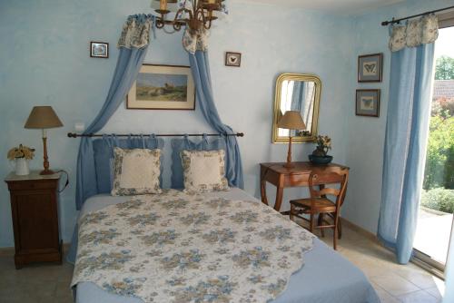 - une chambre avec un lit avec des rideaux bleus et une table dans l'établissement Bastide de l'orme, à Forcalquier