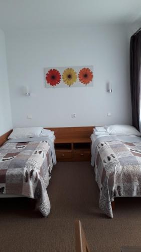 ブスコ・ズドロイにあるPokoje gościnne Busko-Zdrójの花が飾られた壁の客室内のベッド2台