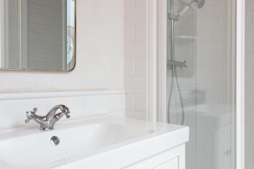 La salle de bains blanche est pourvue d'un lavabo et d'une douche. dans l'établissement Casa Cosi - Eixample 1, à Barcelone