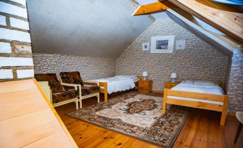 a attic room with two beds and a chair at Gaja-Białowieża in Wiluki