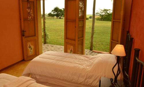 a bedroom with two beds and an open window at Alquimia Posada in Guichón