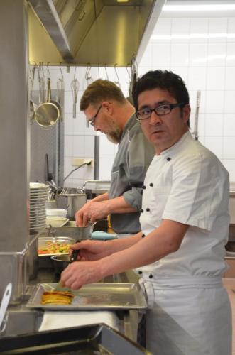 two men standing in a kitchen preparing food at Castell Hotel & Restaurant in Leinsweiler