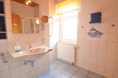 a bathroom with a sink and a window at Hotel & Restaurant Neptun in Norddorf