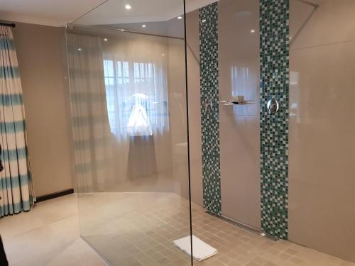 La salle de bains est pourvue d'une douche avec une porte en verre. dans l'établissement The Wilderness Hotel, à Wilderness