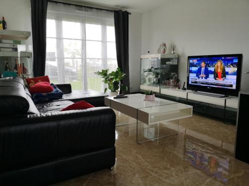 a living room with a couch and a tv at bienvenus chez Éric à Montévrain in Montévrain