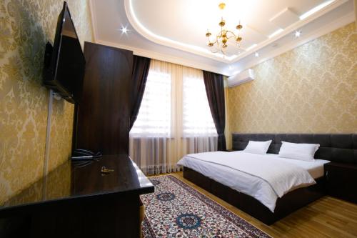 タシュケントにあるAlliance Hotel Tashkentのベッドとテレビが備わるホテルルームです。