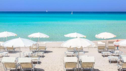 un gruppo di sedie e ombrelloni in spiaggia di La Stratodda Dimora Loft Mare Bandiera Blu 2023 a San Vito dei Normanni