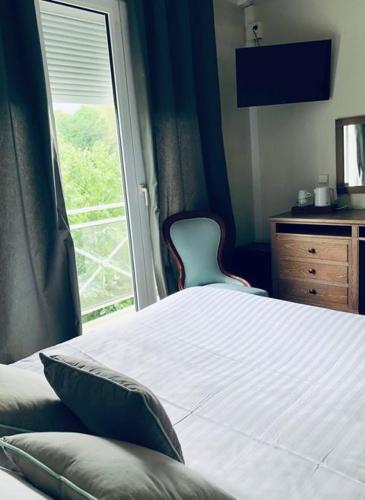 a bedroom with a bed and a window with a chair at Hotel Le Rivage in Olivet
