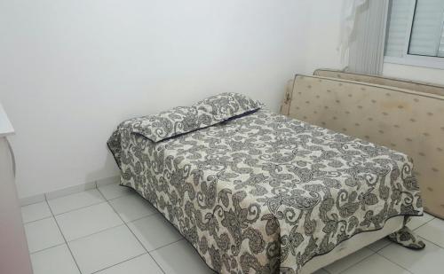 Una cama en una habitación con una manta. en Lindo apartamento bairro Aviação, en Praia Grande