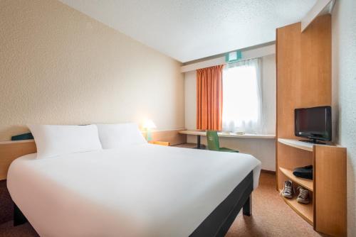 een hotelkamer met een groot bed en een televisie bij ibis Niort Marais Poitevin in Niort