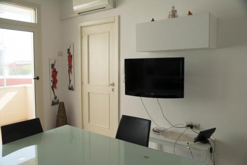 a living room with a table and a television on a wall at Appartamento a due passi dal mare in Torre Lapillo