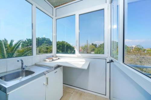 a white bathroom with a sink and a window at Pension Lakis in Prinos