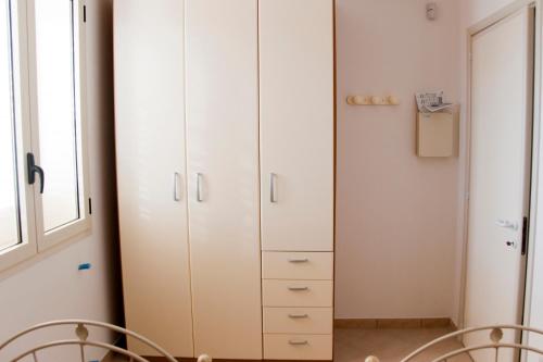 a large white cabinet in a room with chairs at Appartamento a due passi dal mare in Torre Lapillo