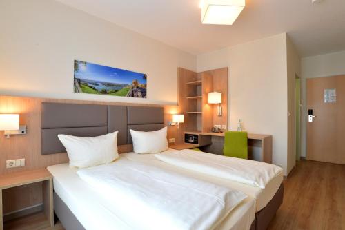 ein Schlafzimmer mit einem großen weißen Bett in einem Zimmer in der Unterkunft City-Hotel Kurfürst Balduin in Koblenz