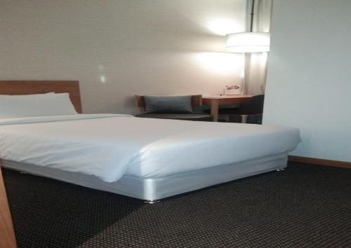 a bedroom with a large white bed and a table at The Vern at BLVD in Nashik