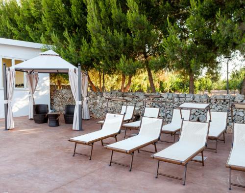 a group of chairs and tables and an umbrella at Masseria Grottella in Avetrana