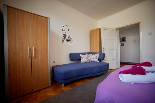 1 dormitorio con 1 cama y 1 sofá azul en Central Tuzla apt - free parking, en Tuzla