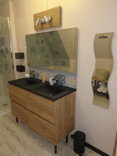 une salle de bain avec un lavabo et un miroir dans l'établissement Grand appartement chaleureux, à Thouars