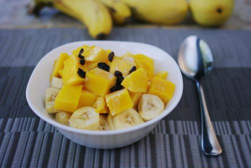 Un tazón de fruta con mangos y chocolate sobre una mesa. en Island Brasserie Hostel, en Corón