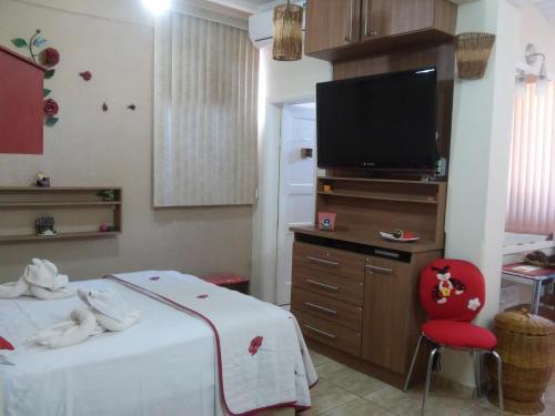 a bedroom with a bed and a tv and a red chair at Apart Hotel em Caxambu207 in Caxambu