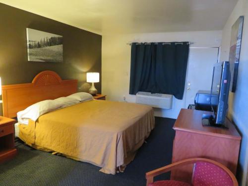 ein Hotelzimmer mit einem Bett und einem Flachbild-TV in der Unterkunft Carquinez Inn in Vallejo