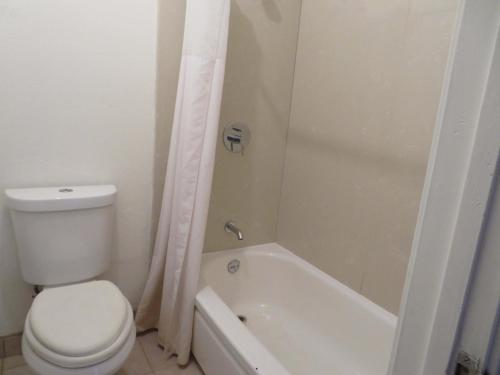uma casa de banho branca com um WC, uma banheira e um WC. em Carquinez Inn em Vallejo