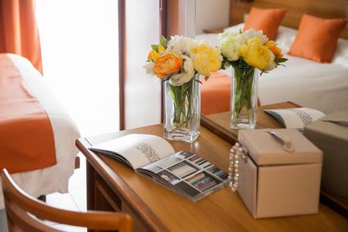 two vases of flowers on a table in a hotel room at Hotel Gilda in Laigueglia