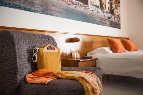a hotel room with a chair and a bed at Hotel Gilda in Laigueglia