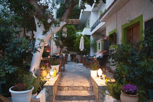 eine Außenterrasse mit einem Tisch, Stühlen und Pflanzen in der Unterkunft Gioma Hotel in Agia Galini