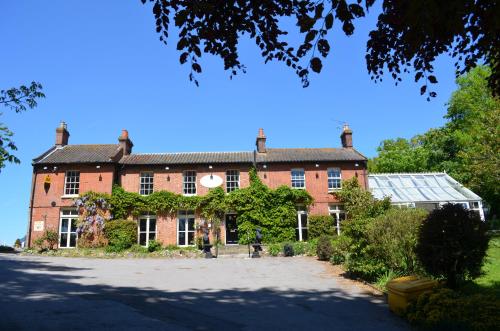 a large red brick building with a greenhouse at Scarborough Hill Country Inn in North Walsham