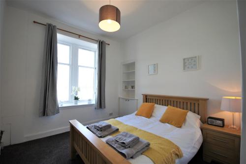 a bedroom with a bed with two towels on it at Bright and Cosy West End Apartment in Glasgow