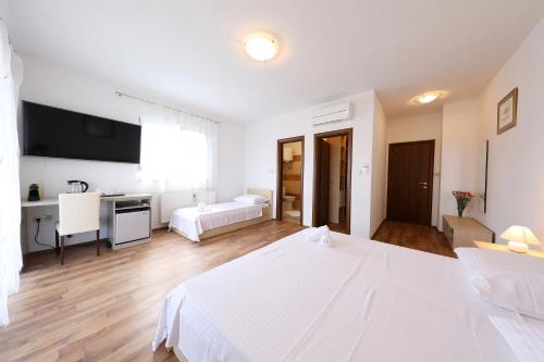 a white bedroom with a large bed and a desk at Villa Magnolia in Privlaka