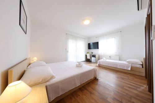 a white bedroom with two beds in it at Villa Magnolia in Privlaka