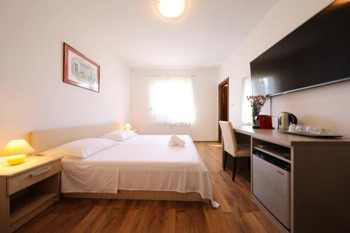 a bedroom with a bed and a desk and a kitchen at Villa Magnolia in Privlaka