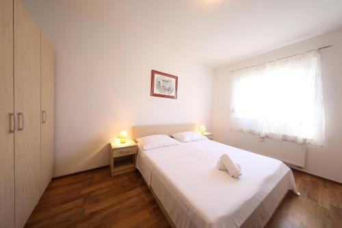 a bedroom with a white bed and a window at Villa Magnolia in Privlaka