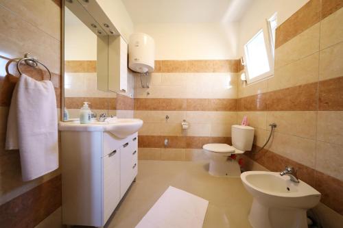 a bathroom with a sink and a toilet and a mirror at Villa Magnolia in Privlaka
