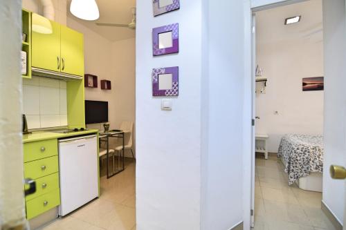 a kitchen with yellow and green cabinets and a bedroom at Apartamentos Marques De La Merced in Málaga