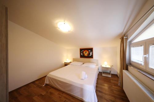 a bedroom with a white bed and a window at Villa Magnolia in Privlaka