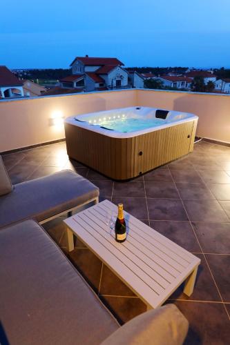a bottle of beer sitting on a bench next to a hot tub at Villa Magnolia in Privlaka