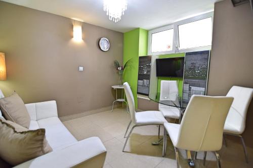 a living room with a table and chairs and a clock at Apartamentos Marques De La Merced in Málaga