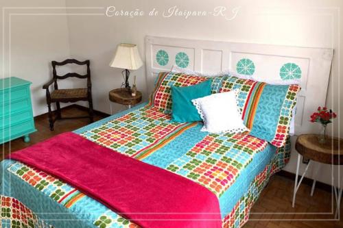 a bedroom with a bed with a colorful comforter at Coração de Itaipava Excelente Localização in Petrópolis