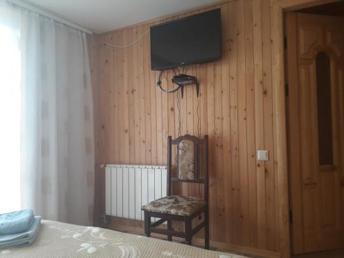 1 dormitorio con TV en la pared y silla en Смериковий, en Yaremche