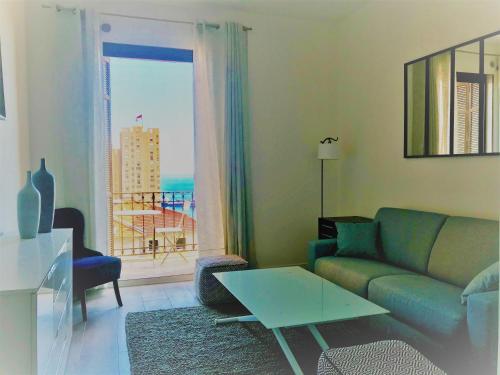 a living room with a couch and a table and a window at villa juturne in Beausoleil