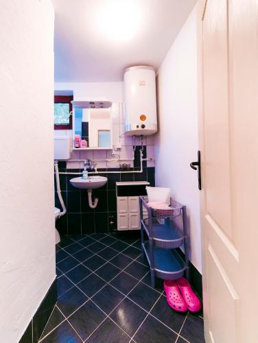 a small kitchen with a sink and pink slippers at Apartmani Slavica in Jagodina