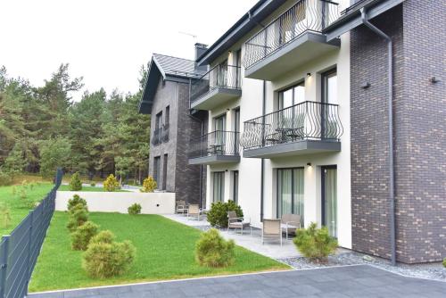 an apartment building with a patio and a yard at Vila Dia Palanga in Palanga