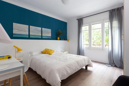 a bedroom with a white bed and a blue wall at Casa Cosi - Eixample 2 in Barcelona