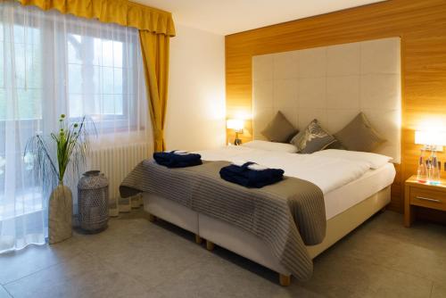 a bedroom with a large bed with blue towels on it at Hotel Diamant Park in Campitello di Fassa