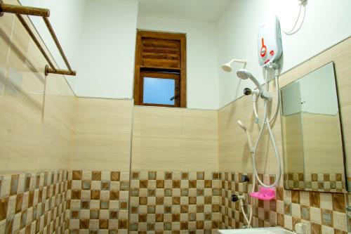 a bathroom with a shower with a sink and a mirror at East Beach Surf Resort in Arugam Bay